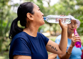 Mature woman drinking water on the public park