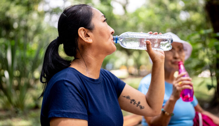 Mature woman drinking water on the public park