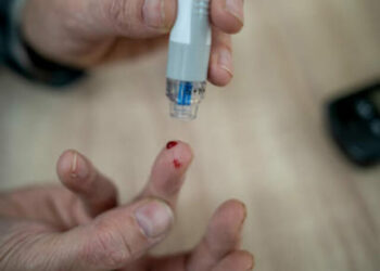 Senior man doing blood sugar test at home