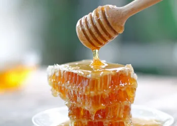 Honey dipper and honeycomb on table