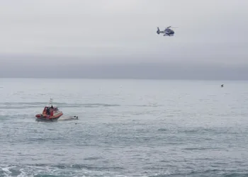 A helicopter and a rescue boat search for survivors off the coast of Kaikoura, New Zealand, Saturday, Sept. 10, 2022. A boat in New Zealand collided with a whale and capsized. (AP Photo)