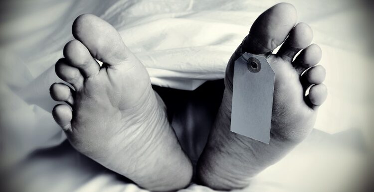 closeup of the feet of a dead body covered with a sheet, with a blank tag tied on the big toe of his left foot, in monochrome, with a vignette added