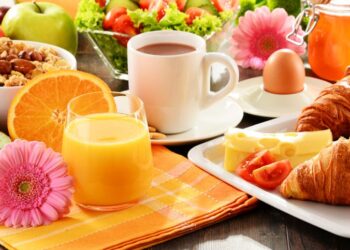 Breakfast consisting of fruits, orange juice, coffee, honey, bread and egg. Balanced diet.