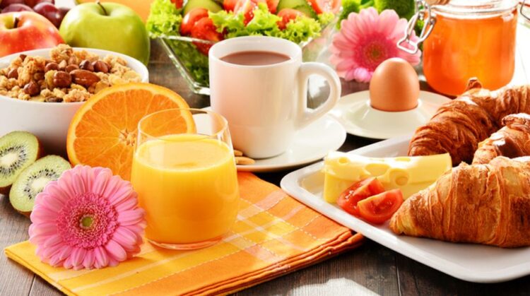 Breakfast consisting of fruits, orange juice, coffee, honey, bread and egg. Balanced diet.