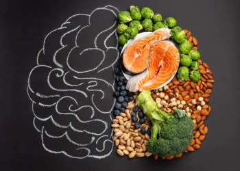 Chalk hand drawn brain with assorted food, food for brain health and good memory: fresh salmon fish, green vegetables, nuts, berries on black background. Foods to boost brain power, top view