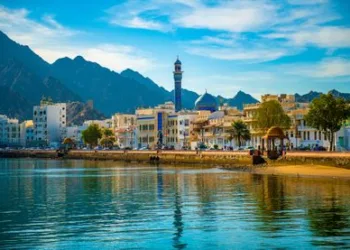 Landscape view of the ancient buildings stretches along the harbor overlooks mountainous rocky formations, Muscat, Oman - December 02, 2018