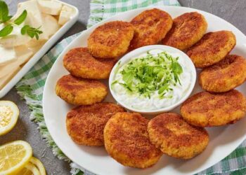 delicious crispy rice cutlets with finely chopped greens on a white platter with yogurt sauce in center and paneer cheese on a rectangular plate, quick and easy recipe, view from above, close-up