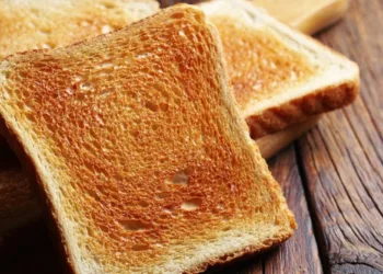 Slices of toasted bread on kitchen board on wooden table close up