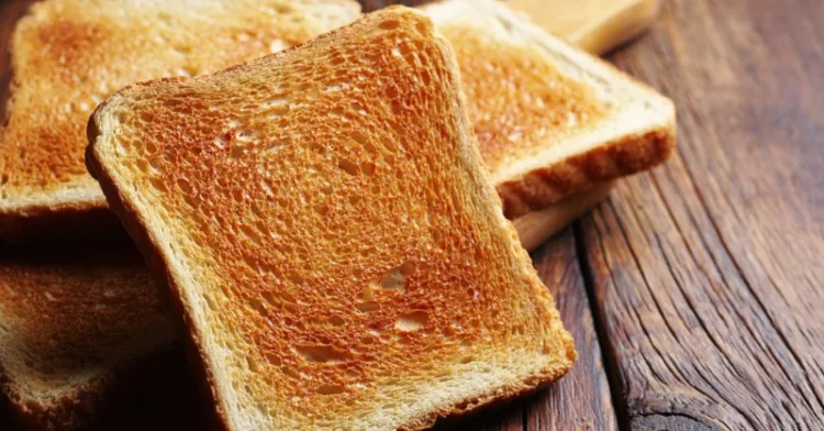 Slices of toasted bread on kitchen board on wooden table close up