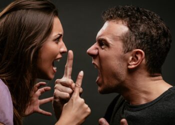 Angry young couple shouting face to face.