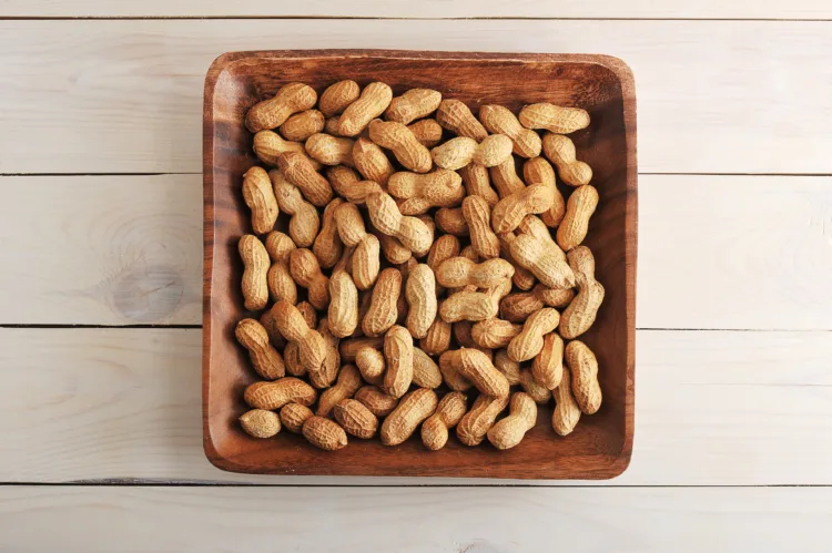 fruits peanut with shell in wooden plate on wooden background - top view