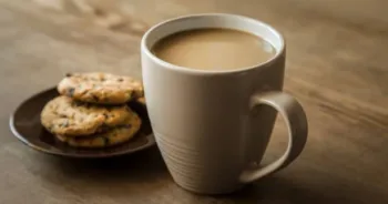 Cup of coffee with milk and cookies with chocolate pieces on the brown wooden table. Resting and enjoying time with coffee and sweets. Drink and snack concept.