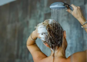 Back view of a woman washing her hair with a shampoo in bathroom. Copy space.