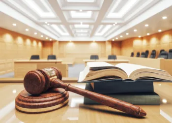 Interior of an empty courtroom with gavel, law books and sounding block on the desk.