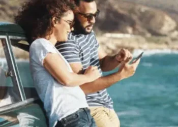 Shot of a young couple using a mobile phone on a road trip