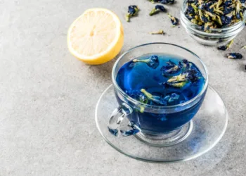 Healthy drinks, organic blue butterfly pea flower tea with limes and lemons, grey concrete background copy space