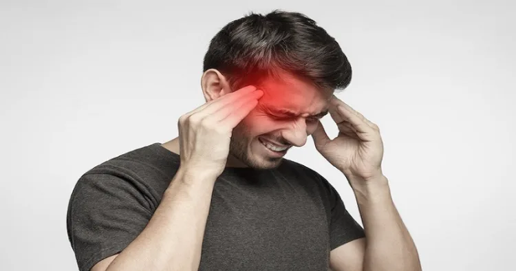 Closeup of young man touching temples with fingers as if suffering from severe migraine, feeling sick, isolated on gray background