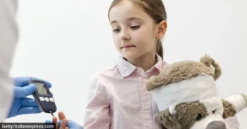 Doctor checking diabetics on equipment of girl with teddybear at clinic