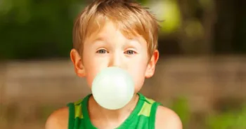 Cute little boy blowing big bubble with gum.