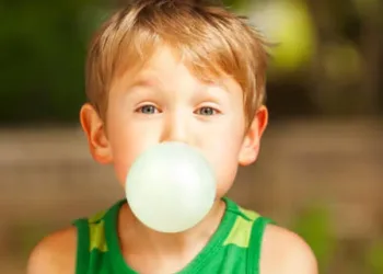 Cute little boy blowing big bubble with gum.
