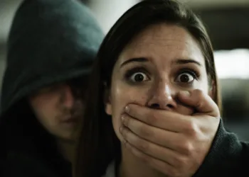 A terrified young woman held captive by a man with his hand over her mouth