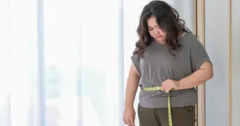 Asian fat women are sad because of the increase in size after checking with a tape measure.