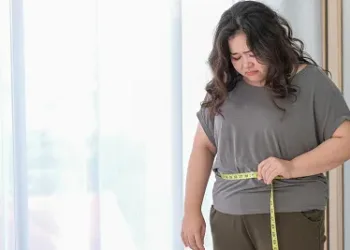 Asian fat women are sad because of the increase in size after checking with a tape measure.