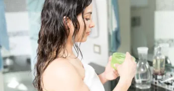 Closeup of a young woman using a skin moisturizer in the bathroom