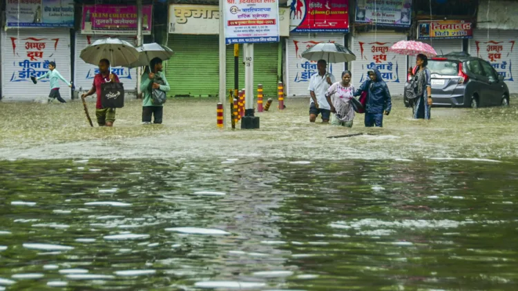 Mumbai: Pedestrians wade through an inundated road amid rains, in Mumbai, Monday, May 26, 2025. (PTI Photo) (PTI05_26_2025_000136B)