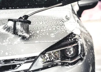 Manual car wash with white soap, foam on the body. Washing Car Using High Pressure Water.