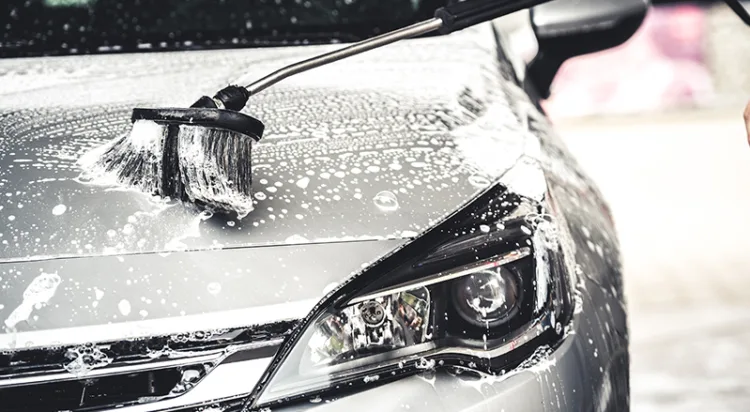 Manual car wash with white soap, foam on the body. Washing Car Using High Pressure Water.