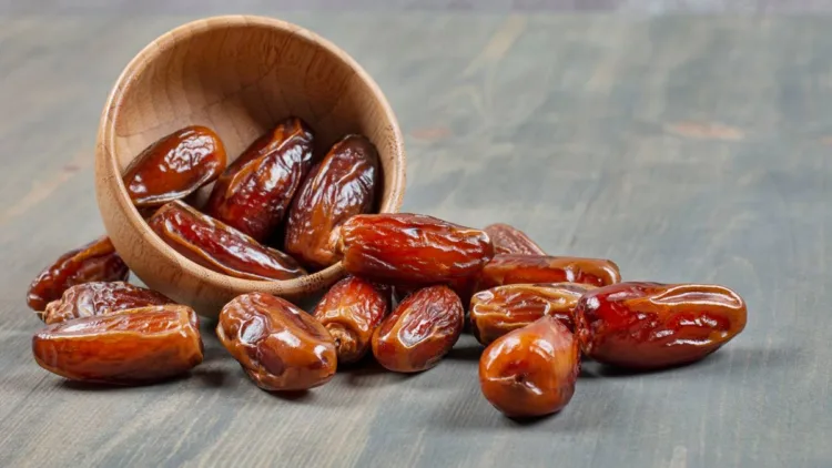 Sweet dates out of wooden bowl on marble background. High quality photo