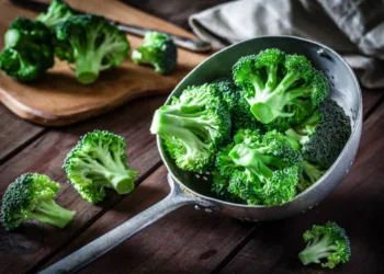 Fresh organic broccoli in an old metal colander shot on rustic wooden table. This vegetable is considered a healthy salad ingredient. Predominant colors are green and brown. Low key DSRL studio photo taken with Canon EOS 5D Mk II and Canon EF 100mm f/2.8L Macro IS USM