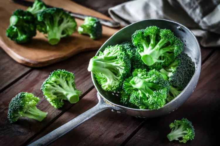 Fresh organic broccoli in an old metal colander shot on rustic wooden table. This vegetable is considered a healthy salad ingredient. Predominant colors are green and brown. Low key DSRL studio photo taken with Canon EOS 5D Mk II and Canon EF 100mm f/2.8L Macro IS USM