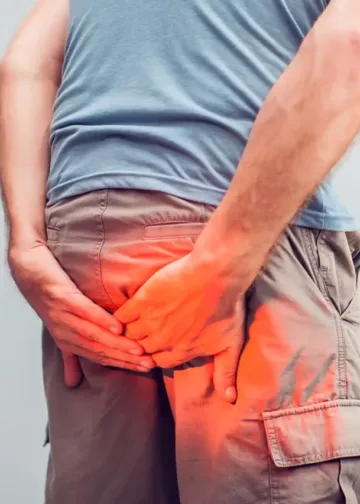 Man-with-hemorrhoids-holding-his-butt-in-pain-in-a-white-background