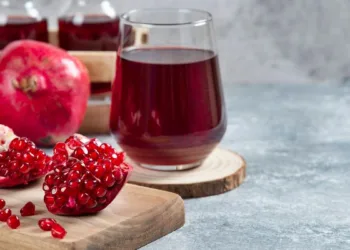 A glass cup of pomegranate juice on a wooden board. High quality photo