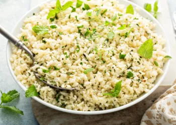 Cauliflower rice with herbs and lemon juice in a white bowl, healthy low carb trendy side dish recipe