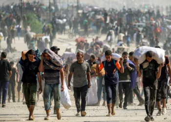 TOPSHOT - People walk with humanitarian aid packages that they received from a distribution centre run by the US and Israeli-backed Gaza Humanitarian Foundation (GHF), at the so-called "Netzarim corridor", in Nuseirat in the central Gaza Strip, on September 30, 2025. The US president on September 29 laid out a plan to end the war in Gaza and Israeli Prime Minister Benjamin Netanyahu said he backed the proposal. The two allies demanded approval by Hamas, whose October 7, 2023 attack triggered a massive Israeli offensive, with Netanyahu warning he will "finish the job" if Hamas says no. (Photo by Eyad BABA / AFP) (Photo by EYAD BABA/AFP via Getty Images)