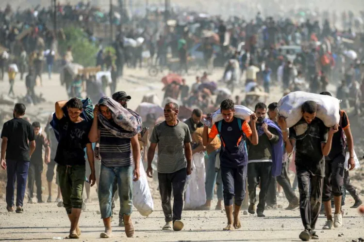 TOPSHOT - People walk with humanitarian aid packages that they received from a distribution centre run by the US and Israeli-backed Gaza Humanitarian Foundation (GHF), at the so-called "Netzarim corridor", in Nuseirat in the central Gaza Strip, on September 30, 2025. The US president on September 29 laid out a plan to end the war in Gaza and Israeli Prime Minister Benjamin Netanyahu said he backed the proposal. The two allies demanded approval by Hamas, whose October 7, 2023 attack triggered a massive Israeli offensive, with Netanyahu warning he will "finish the job" if Hamas says no. (Photo by Eyad BABA / AFP) (Photo by EYAD BABA/AFP via Getty Images)